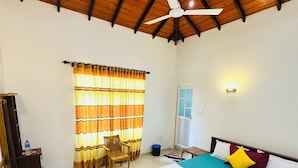 A spacious bedroom with a large bed, a ceiling fan, a wooden ceiling, a window with curtains, and a desk with a chair. - Ahasna Family Villa (Negombo)