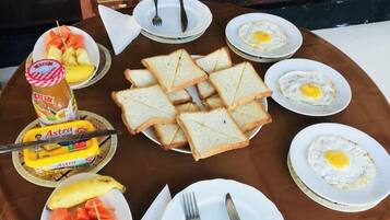 A breakfast setup with toast, eggs, jam, butter, and fruit on a wooden table.