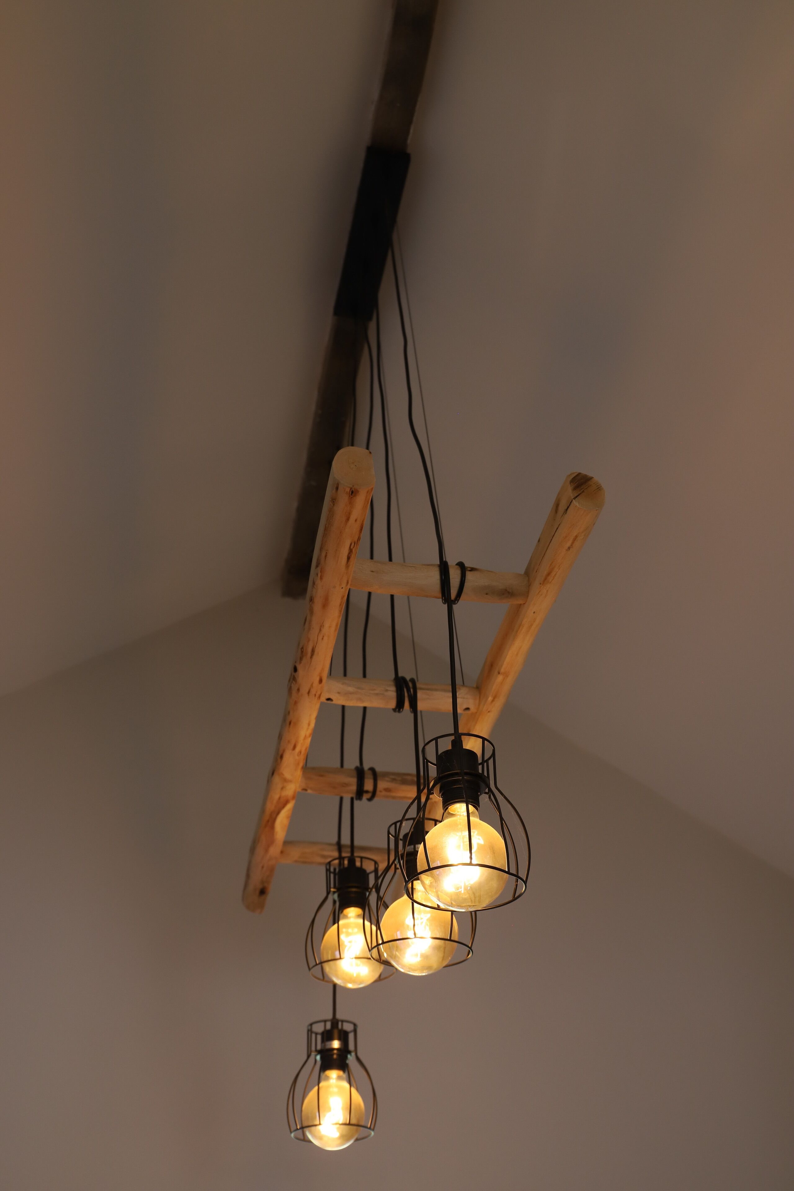 A ceiling with exposed wooden beams and hanging light fixtures.