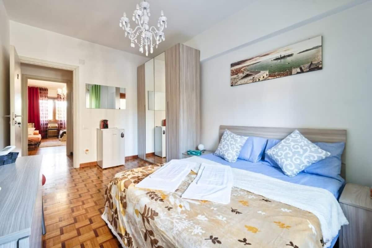 Un dormitorio con cama, escritorio, silla, armario y un cuadro en la pared.
