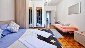 Une chambre avec deux lits, un lustre, un miroir et une armoire.