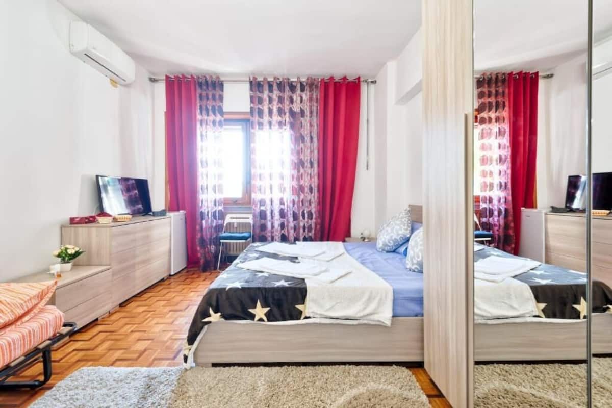 Un dormitorio con dos camas, un aparador, un televisor y un espejo.