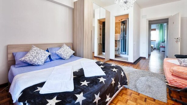 Une chambre à coucher avec un lit, un lustre, un miroir et un dressing.