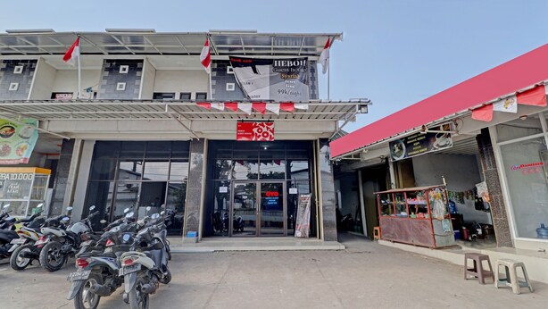 A hotel with a guest house, a sign for a 99K/night rate, and several motorcycles parked in front. - OYO Life 90570 Heboh Guest House Syariah (Majalaya)