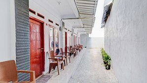 A corridor with rows of wooden chairs and a row of red doors, likely leading to rooms or offices. - OYO Life 90570 Heboh Guest House Syariah (Majalaya)