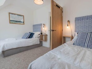 Two single beds with matching headboards and bedside tables, featuring white linens and decorative pillows.