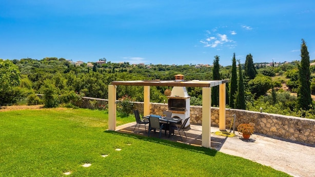 A patio with a grill, chairs, and a view of a vineyard and hills. - Europe Villa Io - Two Bedroom Villa, Sleeps 4 (Ionian Islands)