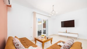 A living room with two brown sofas, a wooden coffee table, and a TV on a white cabinet. - Europe Villa Io - Two Bedroom Villa, Sleeps 4 (Ionian Islands)