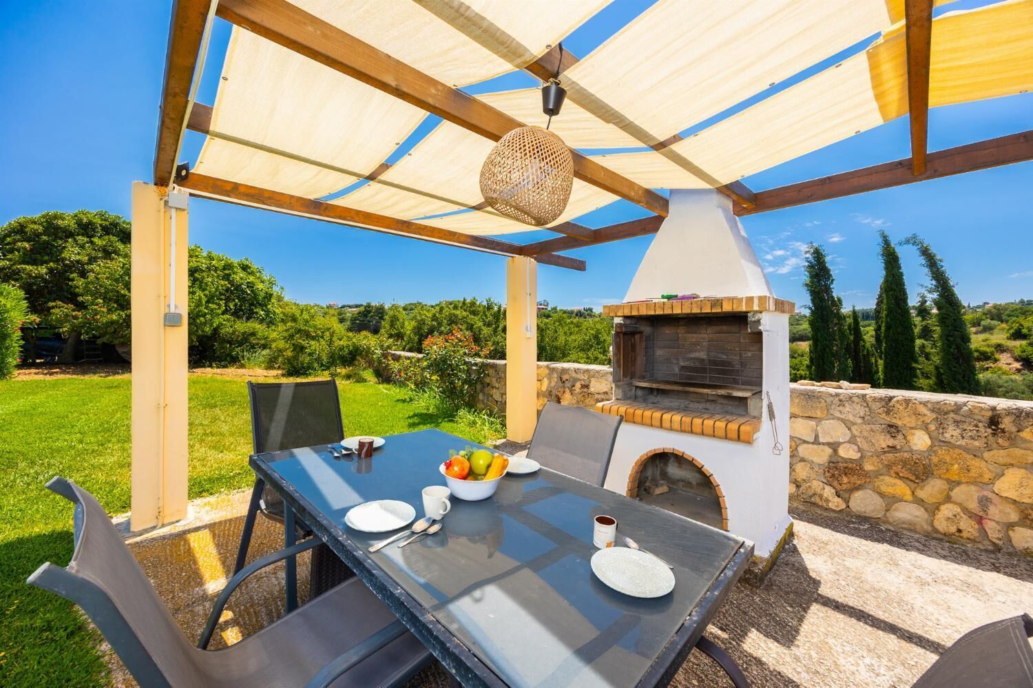 Eine Außenpatio mit Esstisch, integriertem Grill und Pergola darüber.
