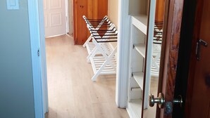 Un couloir avec un plancher en bois, une porte blanche sur la gauche et une porte en bois sur la droite.
