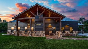 A rustic building with a 'Welcome' sign, stone pillars, and a covered porch with lights. - South Texas Ranch Getaway (Goliad)