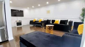 Ein modernes Wohnzimmer mit einer schwarzen Sofagarnitur, einem runden Couchtisch und einem flachbildfernseher, der an der Wand befestigt ist.