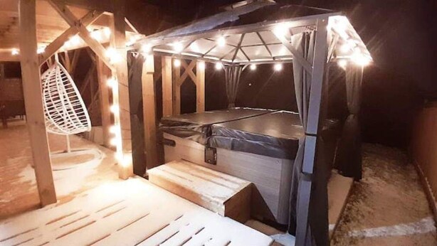 Ein gemütlicher Schlafbereich im Freien mit erhöhter Plattform und Baldachin, beleuchtet von Lichterketten.