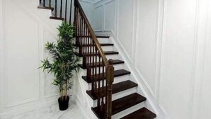 Eine Treppe mit Holzhäuschen und Handlauf, die zu einer Zwischenebene mit einem Blumentopf führt.