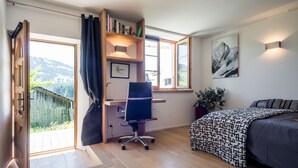 A bedroom with a desk, a bed, a bookshelf, and a window with a view of the outdoors. - Appartement 50m2 Megève/demi-quartier, vue Mt Blanc, Atelier D'artiste Rénové (Demi-Quartier)