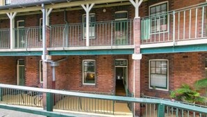 Un edificio de ladrillo de varios pisos con balcones y barandilla verde.
