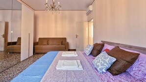 A hotel room with a bed, a sofa, a chandelier, and a wardrobe. - Venice Magic Night Apartment (Mestre)
