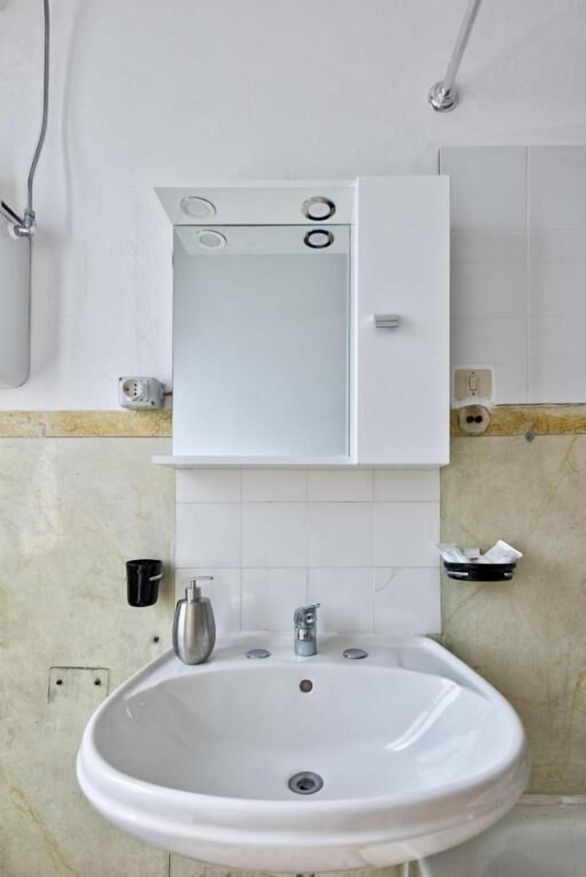A bathroom with a white sink, a mirror above it, and a towel rack to the right.
