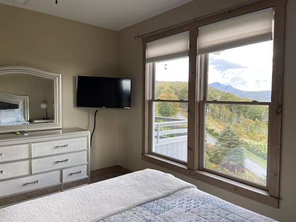 A bedroom with a bed, dresser, and a TV mounted on the wall.