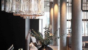 A modern interior with a hanging light fixture made of glass bulbs and a vase with green foliage. - Four Points Flex by Sheraton Hillerød (Hillerod)