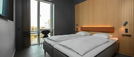 Una habitación de hotel moderna con dos camas, un escritorio y vistas a la ciudad.