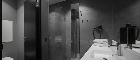 A modern bathroom with a glass shower enclosure, a white sink, and a large mirror.