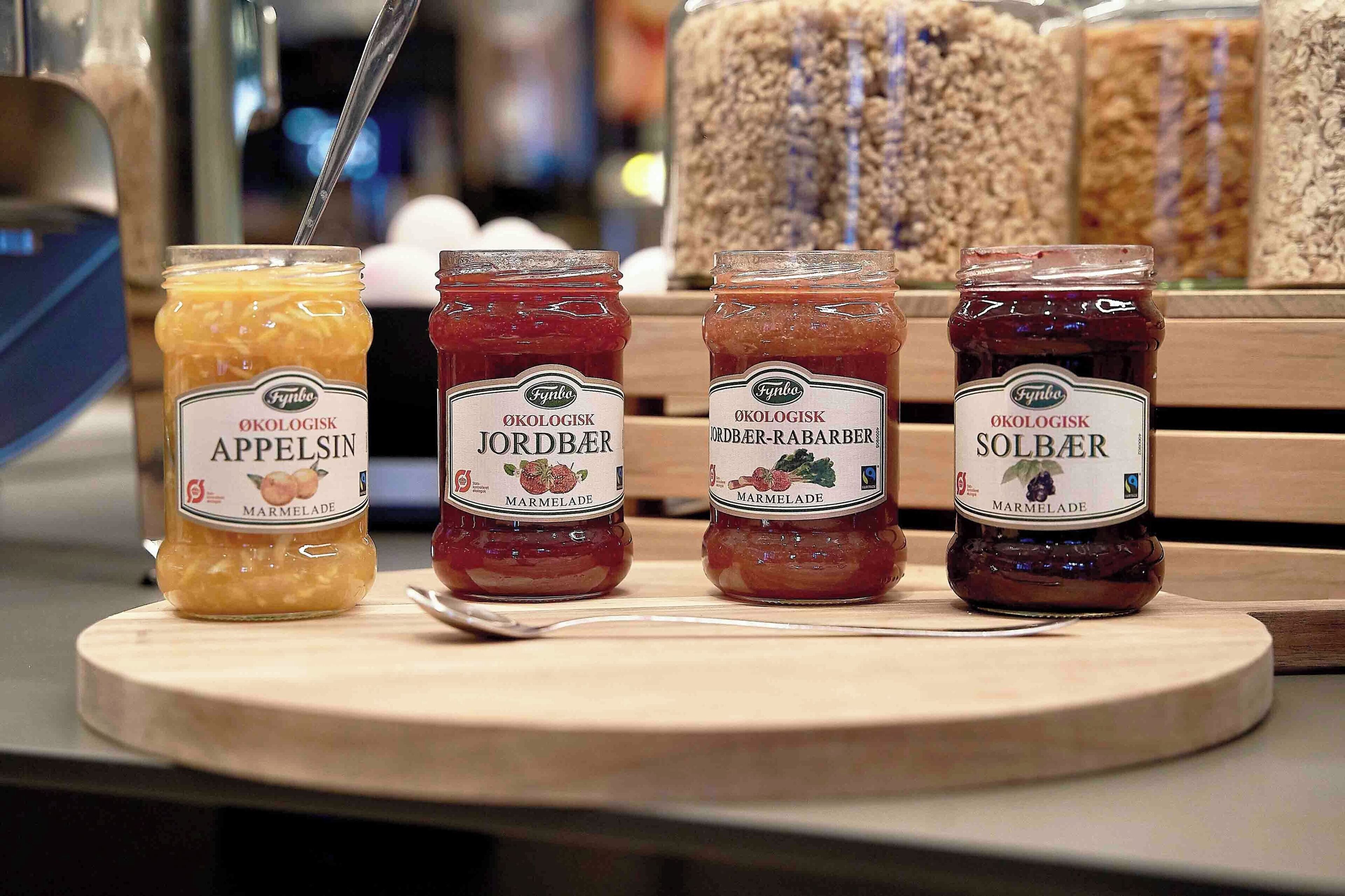 Four jars of marmalade on a wooden board.