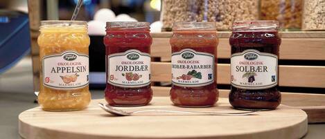 Four jars of marmalade on a wooden board.
