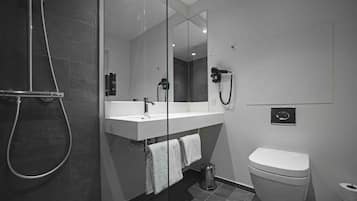 Un baño moderno con ducha envuelta en vidrio, un lavabo blanco con espejo y un inodoro.