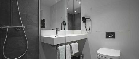 A modern bathroom with a glass-enclosed shower, a white sink with a mirror, and a toilet.