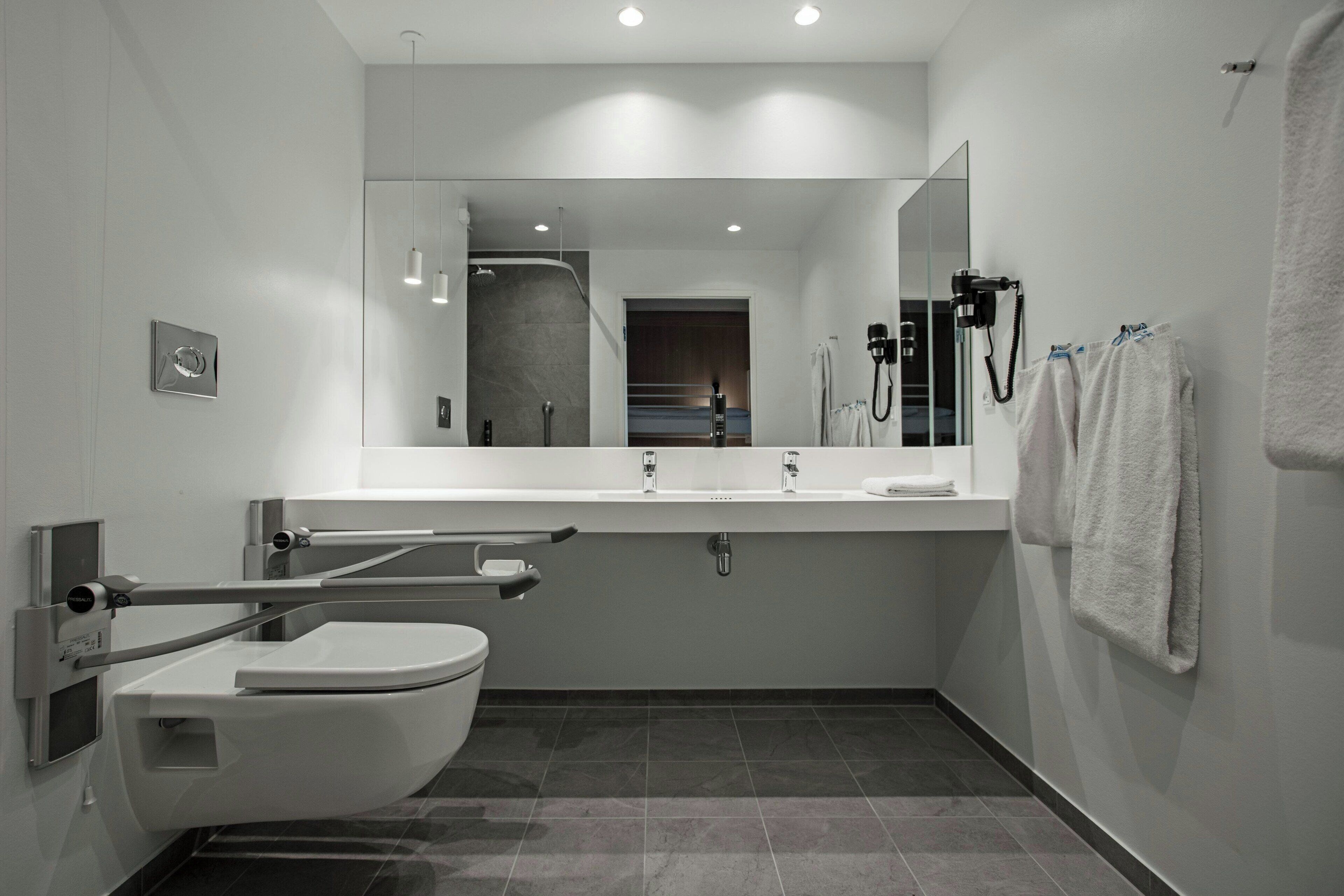 Un baño moderno con inodoro, bidé, lavabo y espejo.