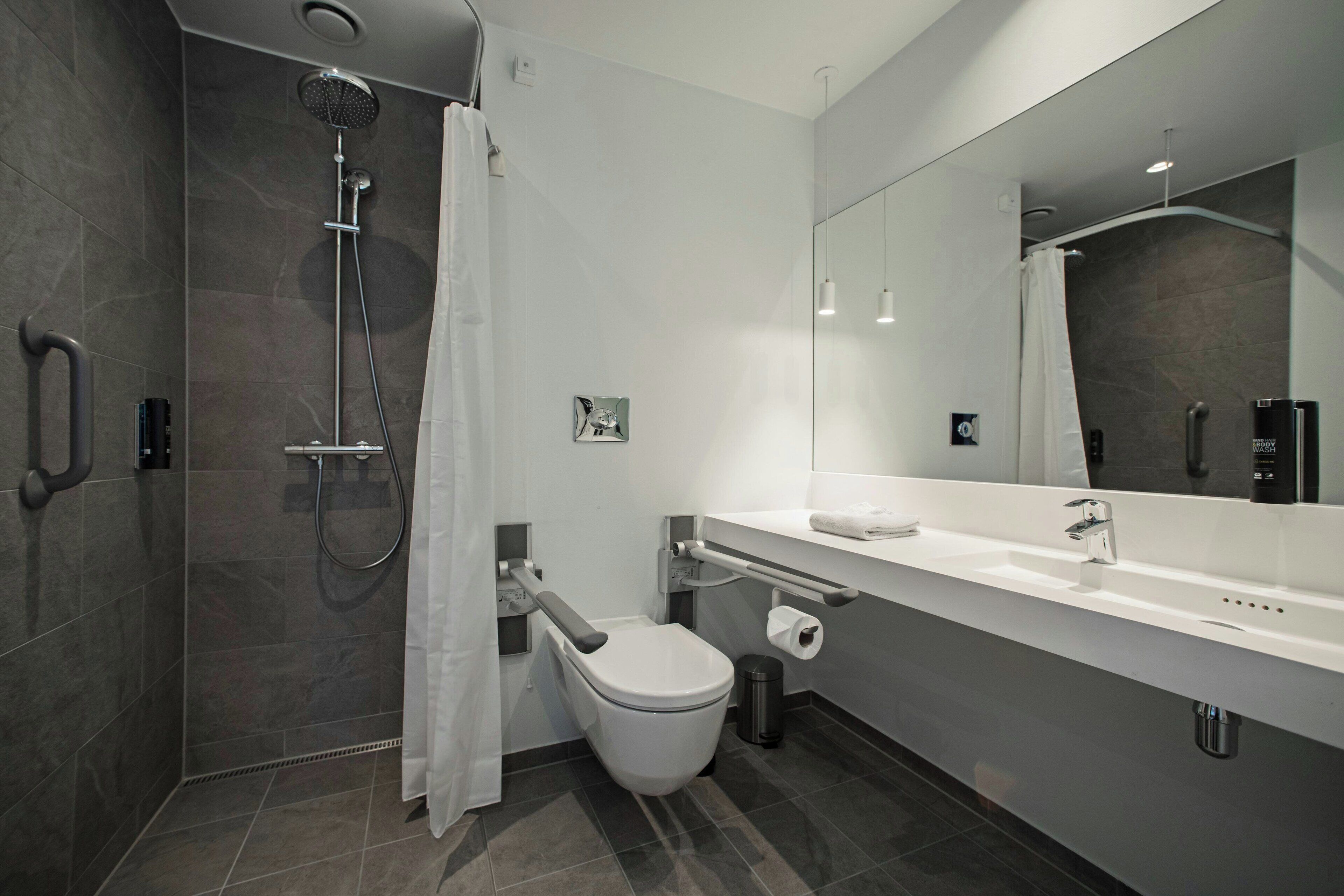A modern bathroom with a shower, toilet, and sink.