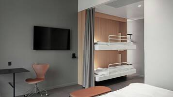 A modern hotel room with a bunk bed, a desk with a chair, and a flat-screen TV on the wall.