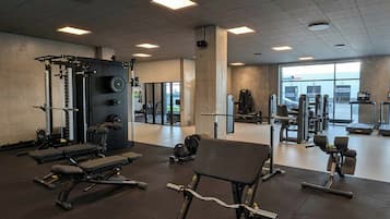 Et fitnessrum med vægte, træningsbænke og konditionsmaskiner.