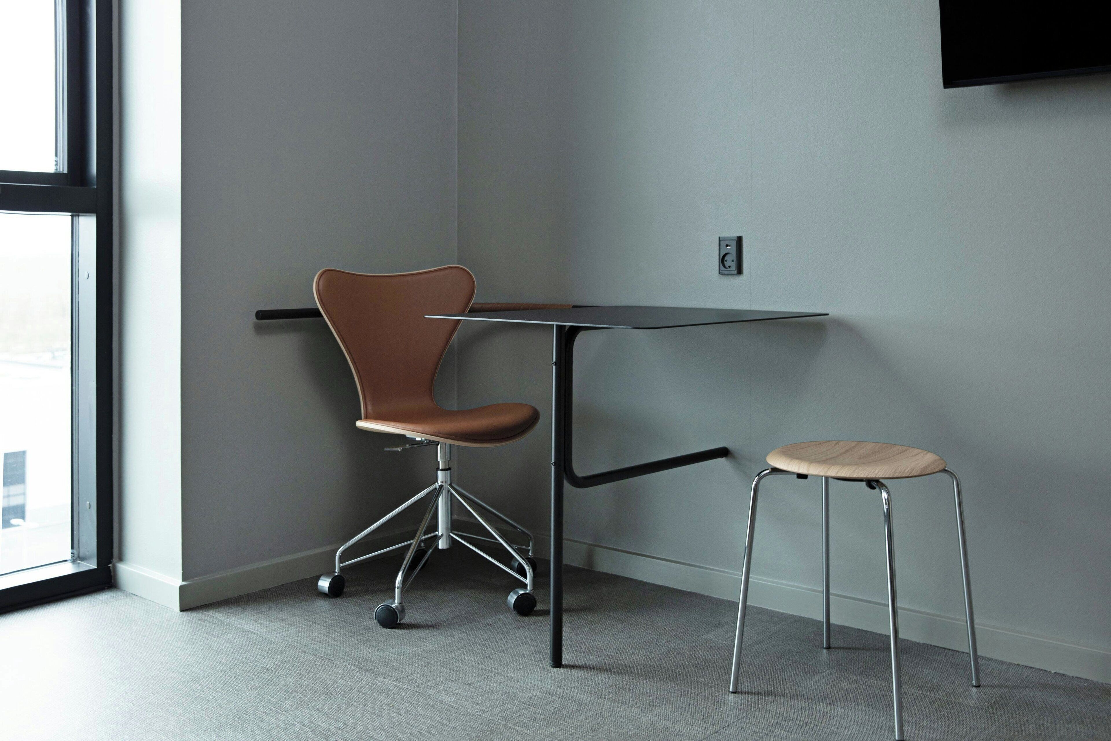 A modern room with a swivel chair, a small stool, and a flat-screen TV mounted on the wall.