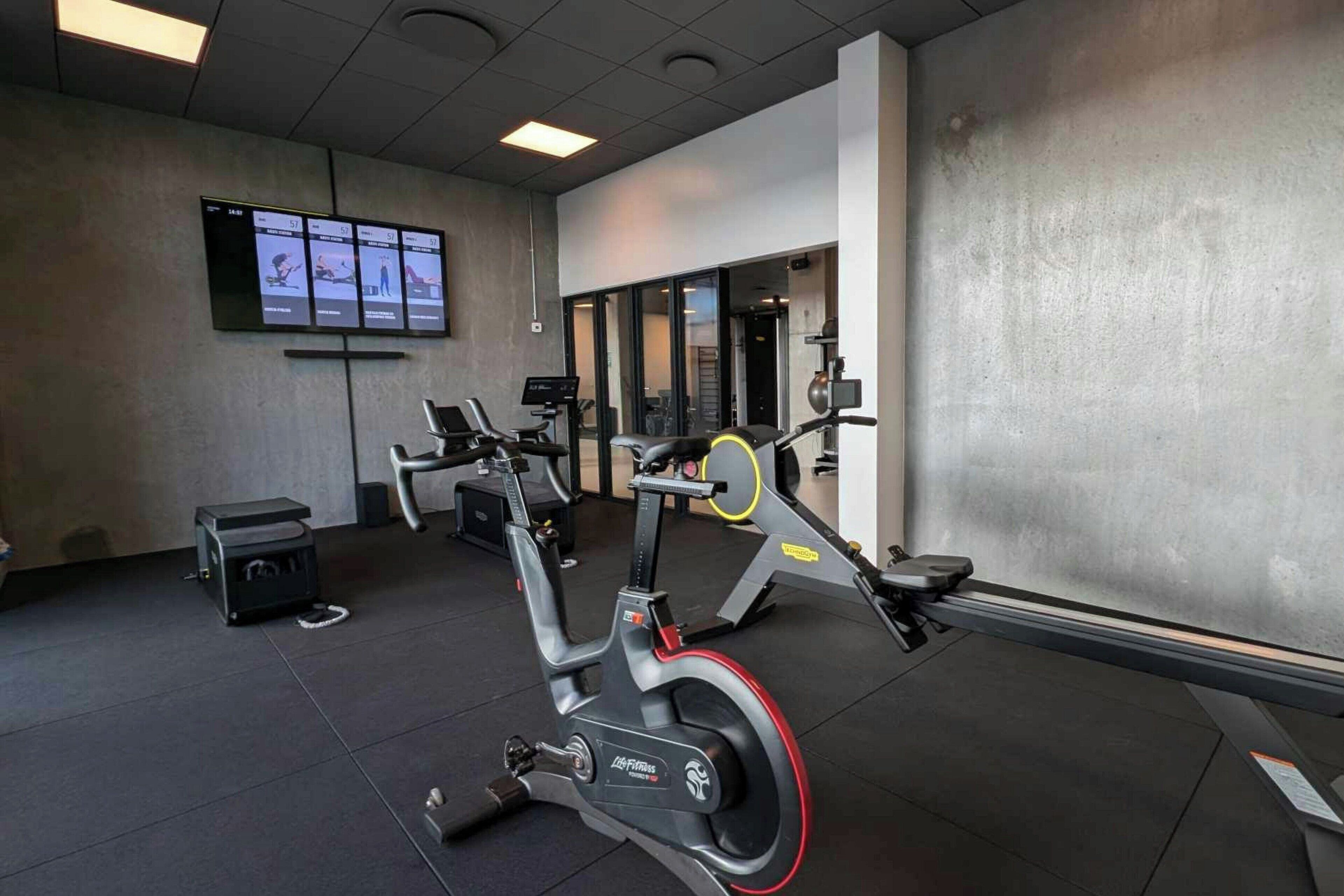 Un gimnasio con bicicletas estáticas, una cinta de correr y máquinas de pesas.