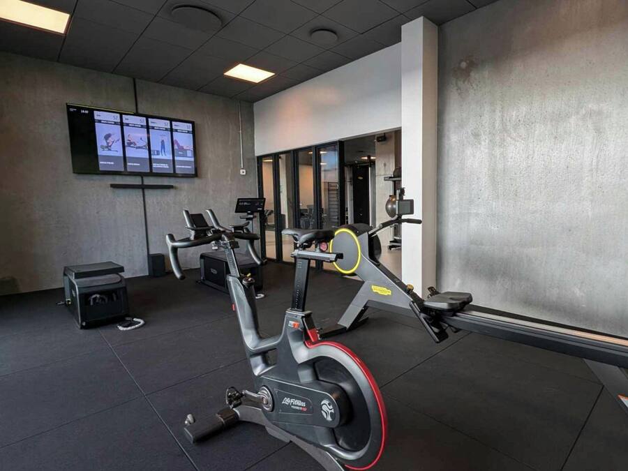 Un gimnasio con bicicletas estáticas, una cinta de correr y máquinas de pesas.