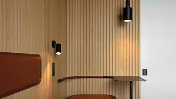 Ein modernes Interieur mit einer Wand aus Holzpaneelen, einer braunen Lederbank und einer schwarzen Pendelleuchte.