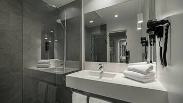 A modern bathroom with a glass shower enclosure, a white sink, and a large mirror.