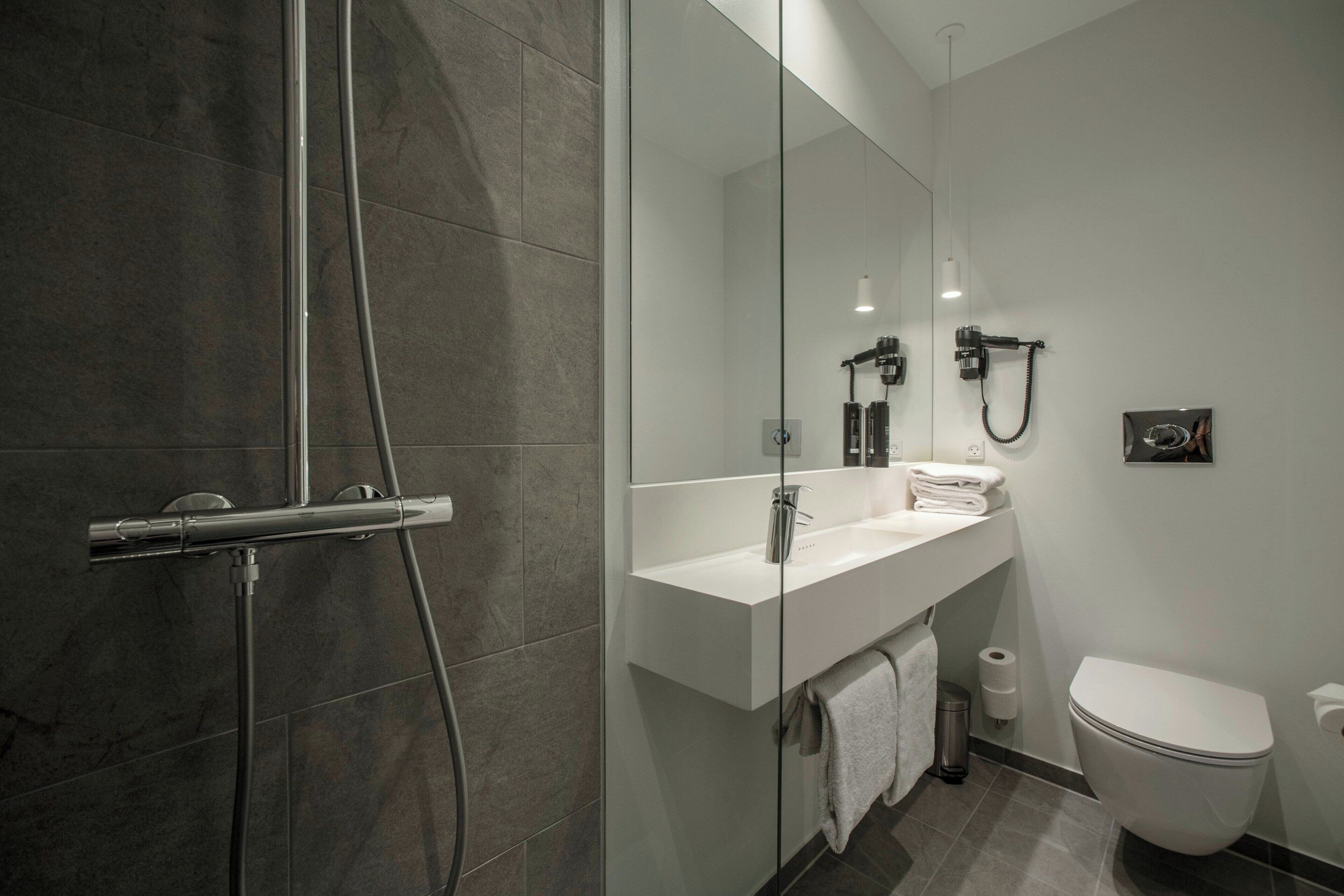 A modern bathroom with a glass shower enclosure, a white sink, and a toilet.