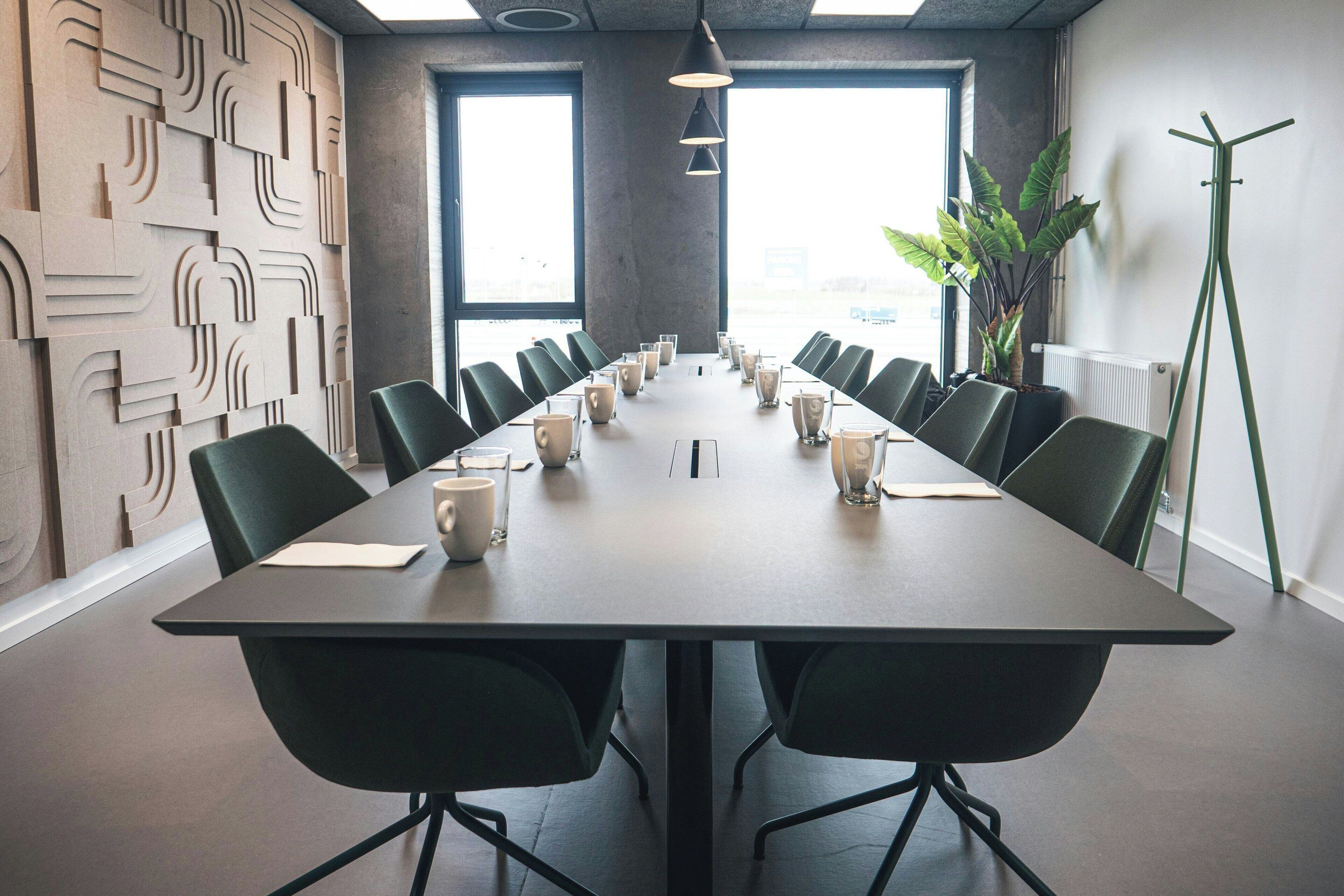 A conference room with a long table, chairs, and a potted plant.