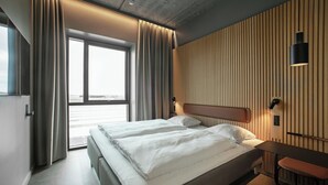Une chambre d’hôtel moderne avec deux lits, une grande fenêtre et une vue sur la ville.
