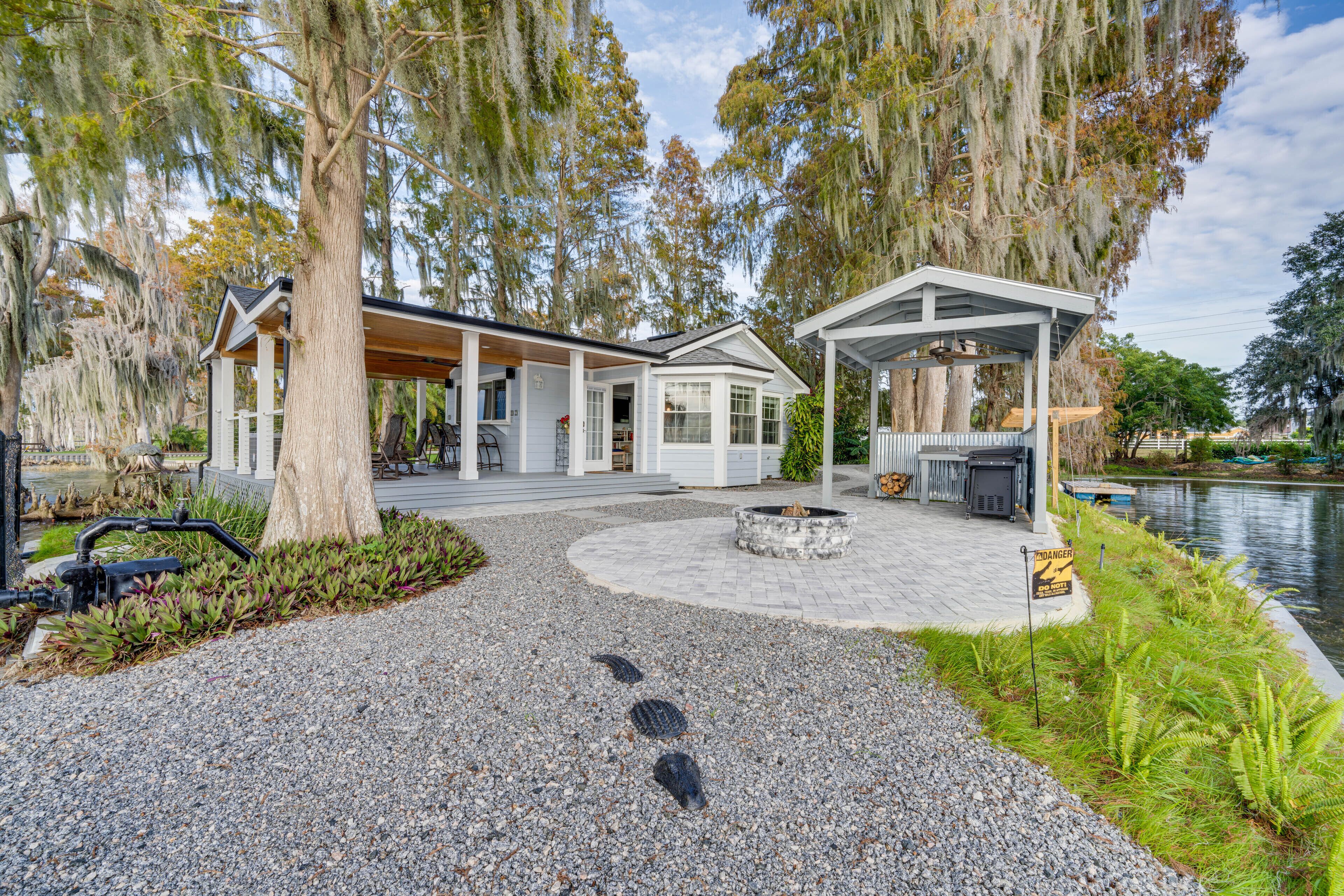 A modern house with a covered patio, a pond, and a fire pit.