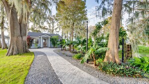 Un sendero lleva a una casa rodeada de árboles y plantas.