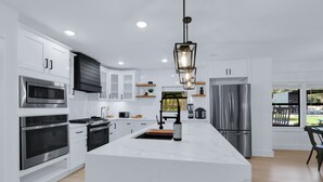 Een moderne keuken met witte kasten, roestvrijstalen apparatuur en een marmeren eiland.