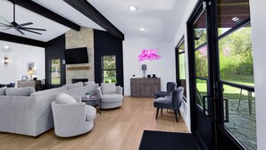 Een moderne woonkamer met een modulaire bank, fauteuils, een open haard en een groot raam met uitzicht op de omgeving.
