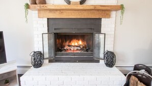 Une cheminée avec un encadrement en briques blanches, une cheminée en bois et deux vases décoratifs.