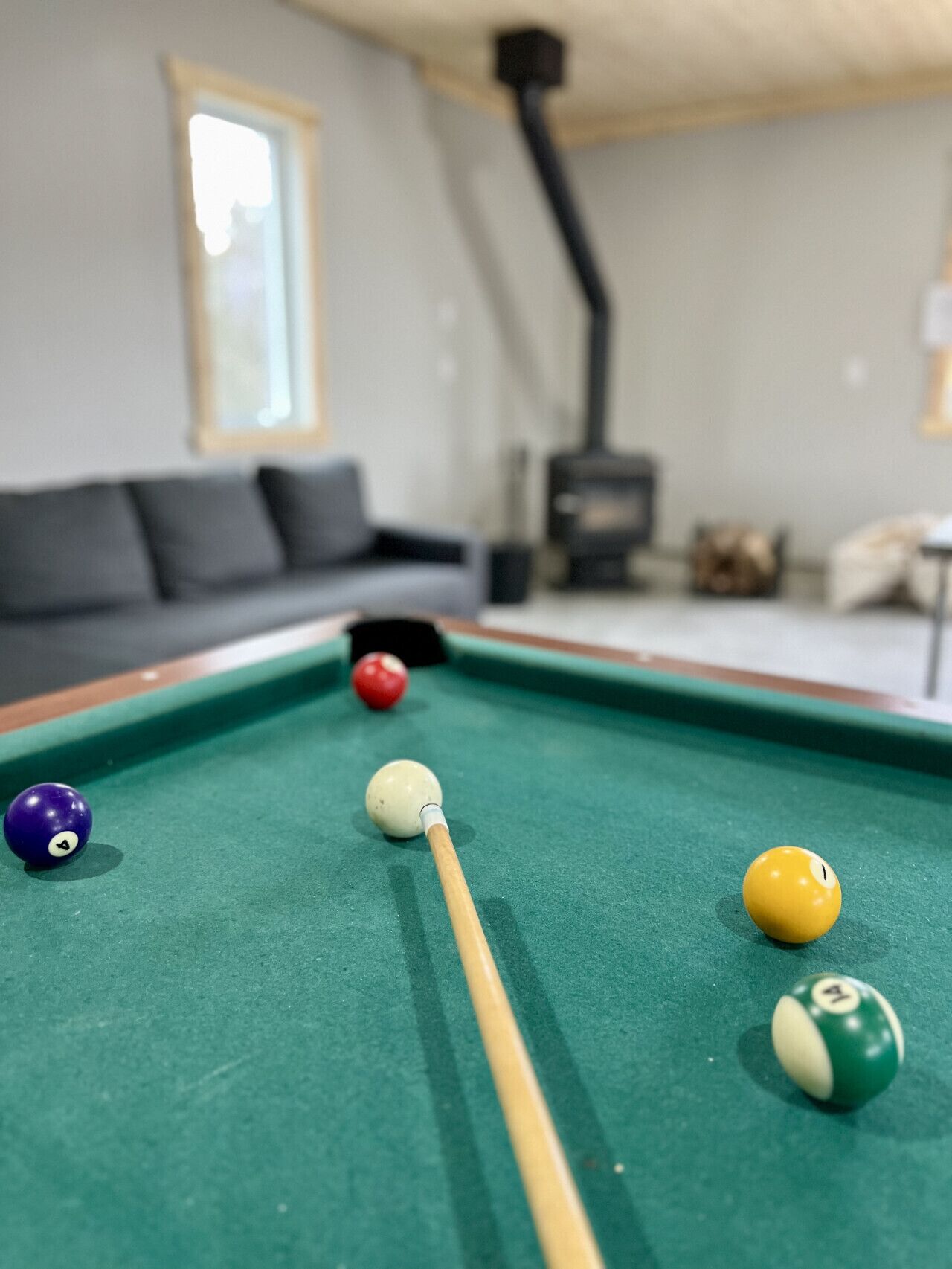 Une table de billard avec des billes, dans une pièce où se trouvent un canapé et une cheminée.