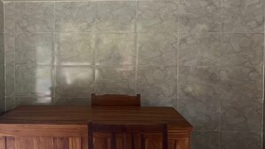 A wooden dining table with a chair in a room with tiled walls. - OYO Life 93401 Kos Putri Alamanda Syariah (Janapria)