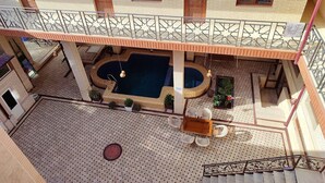 A multi-level building with a central courtyard featuring a swimming pool, outdoor seating, and a staircase. - hotel Shams Bukhara (Bukhara)